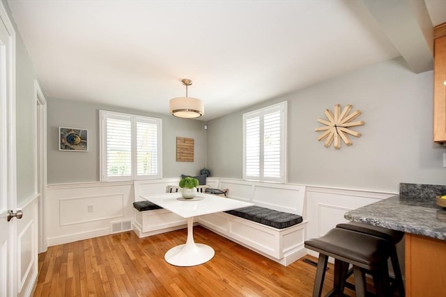 dining room with plenty of natural light, a wainscoted wall, and visible vents