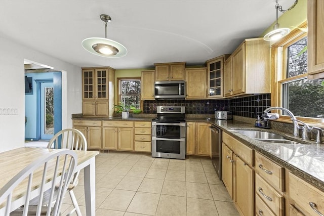 kitchen with light tile patterned floors, stainless steel appliances, decorative backsplash, hanging light fixtures, and sink