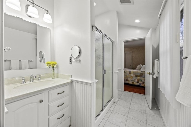 bathroom featuring a shower with shower door, vanity, vaulted ceiling, and tile patterned flooring