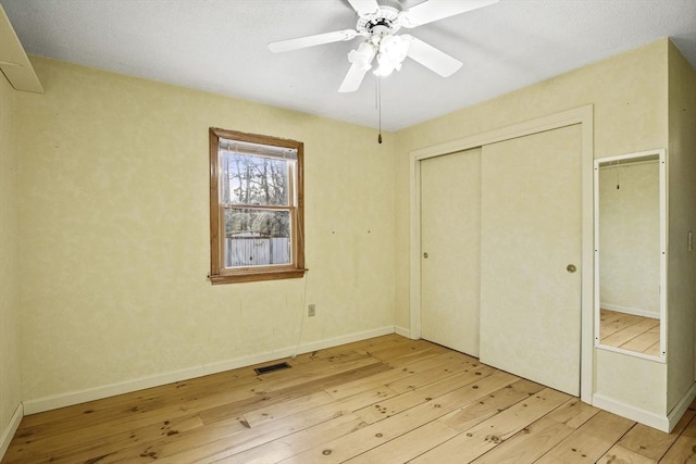 unfurnished bedroom with ceiling fan, a closet, and light hardwood / wood-style floors