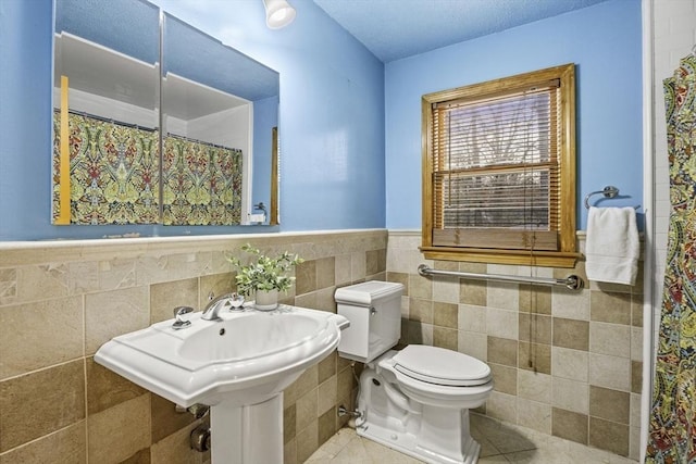 bathroom featuring toilet, tile walls, tile patterned floors, and a shower with shower curtain