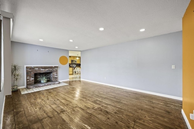 unfurnished living room with a textured ceiling, a fireplace, and hardwood / wood-style floors