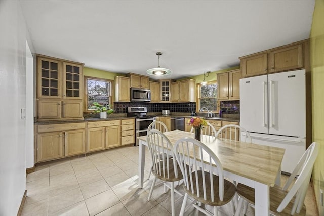 kitchen featuring light tile patterned floors, appliances with stainless steel finishes, decorative backsplash, hanging light fixtures, and sink