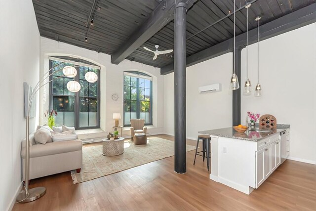 living room featuring beamed ceiling, wooden ceiling, rail lighting, light wood finished floors, and baseboards