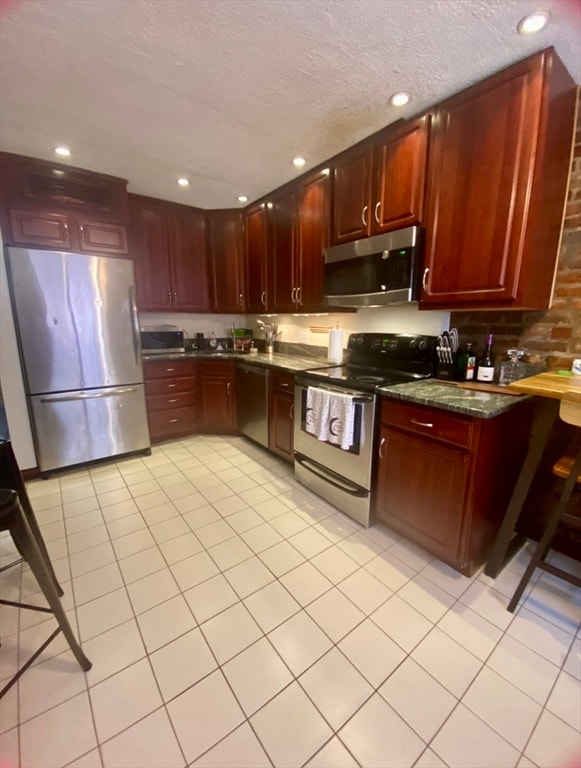 kitchen featuring a textured ceiling, light tile patterned flooring, and stainless steel appliances