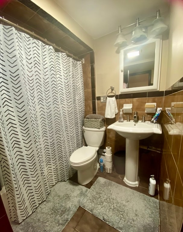 bathroom with a shower with curtain, tile walls, tile patterned flooring, and toilet