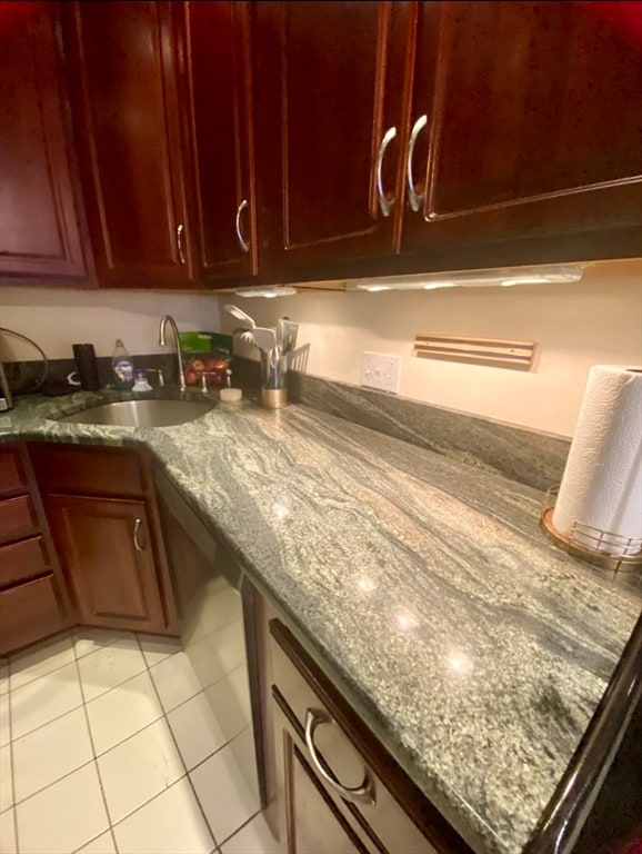 kitchen with dark stone countertops, light tile patterned floors, and sink