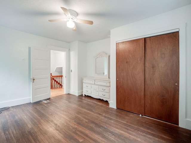 unfurnished bedroom with dark hardwood / wood-style flooring, a closet, and ceiling fan