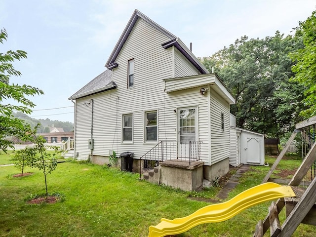 back of property with a yard and a playground