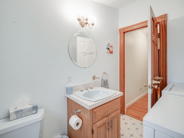 bathroom with toilet, washing machine and clothes dryer, and vanity