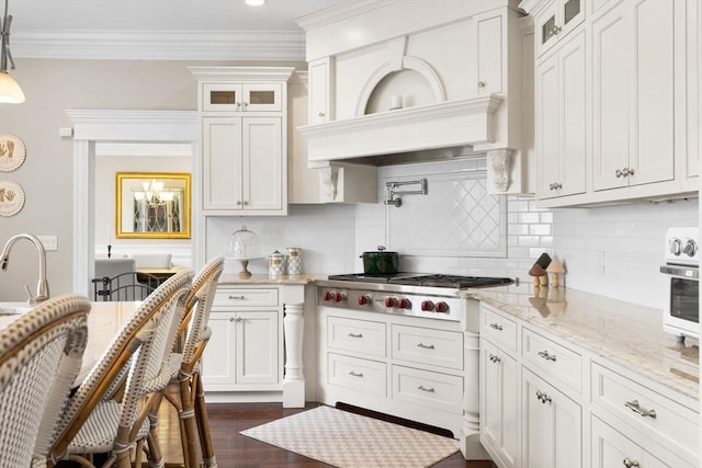 kitchen with tasteful backsplash, glass insert cabinets, crown molding, and stainless steel gas stovetop