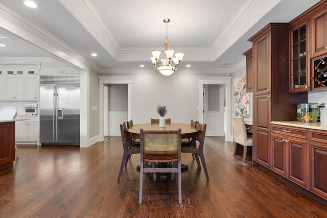 dining room featuring an inviting chandelier, a tray ceiling, crown molding, and dark wood finished floors