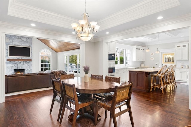 dining area with crown molding, a notable chandelier, a fireplace, and dark wood-style flooring