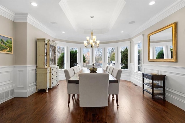 dining area featuring visible vents, a wainscoted wall, a tray ceiling, dark wood-style floors, and a chandelier