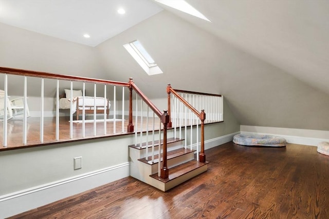 stairway with vaulted ceiling with skylight, wood finished floors, and baseboards