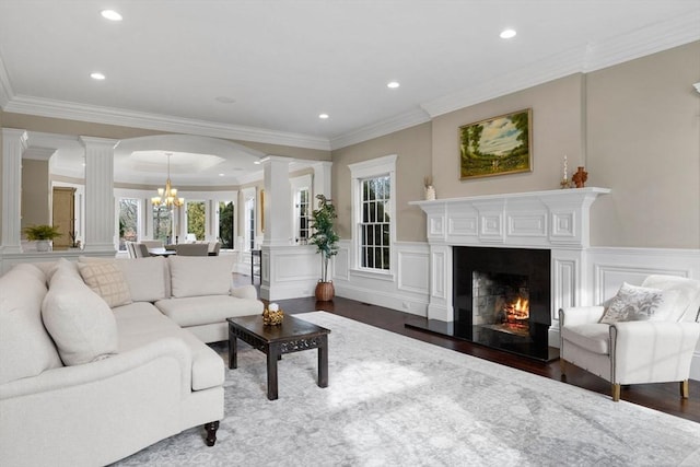 living room with dark wood finished floors, a notable chandelier, a decorative wall, and decorative columns