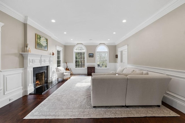 living room with a wainscoted wall, ornamental molding, recessed lighting, a fireplace, and wood finished floors