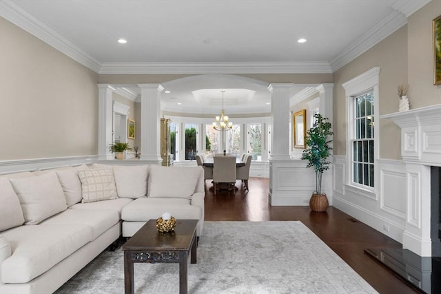 living room featuring dark wood-type flooring, a wainscoted wall, ornate columns, and a chandelier