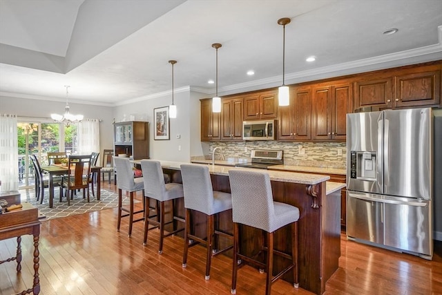 kitchen featuring a kitchen island with sink, appliances with stainless steel finishes, tasteful backsplash, and dark wood-type flooring