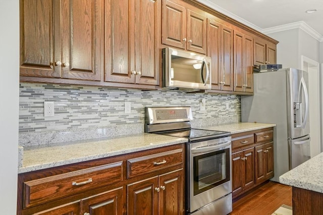 kitchen with crown molding, dark wood-type flooring, tasteful backsplash, light stone counters, and stainless steel appliances