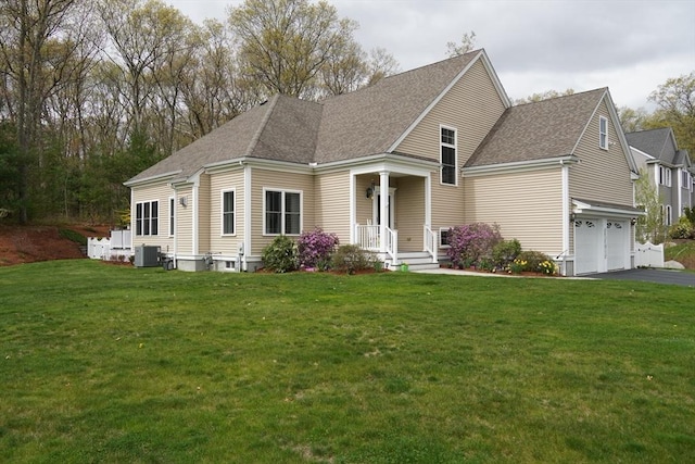 view of front of home with an attached garage, central AC unit, a front lawn, and aphalt driveway