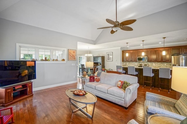 living area with ornamental molding, dark wood-style flooring, lofted ceiling, baseboards, and ceiling fan with notable chandelier