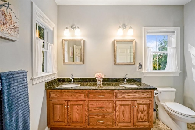 bathroom with a sink, toilet, and double vanity