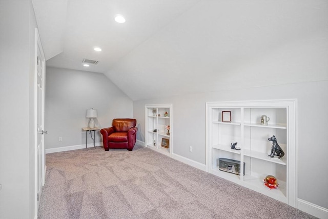 living area featuring visible vents, lofted ceiling, baseboards, built in shelves, and carpet