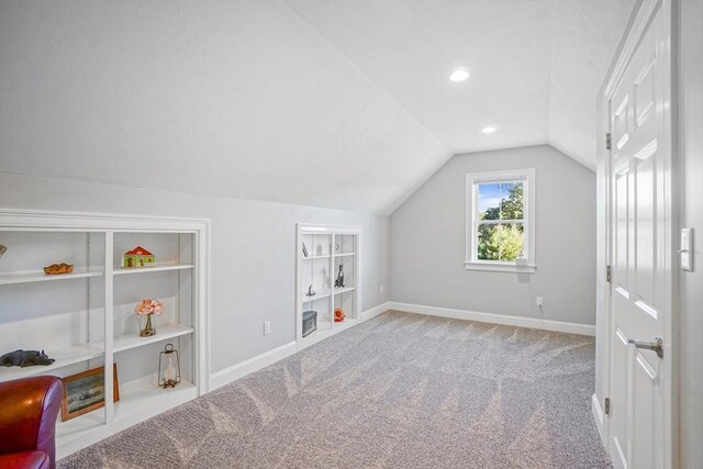 additional living space with carpet floors, baseboards, vaulted ceiling, and built in features