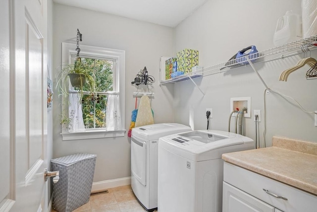 laundry area featuring laundry area, visible vents, washing machine and dryer, light tile patterned flooring, and baseboards