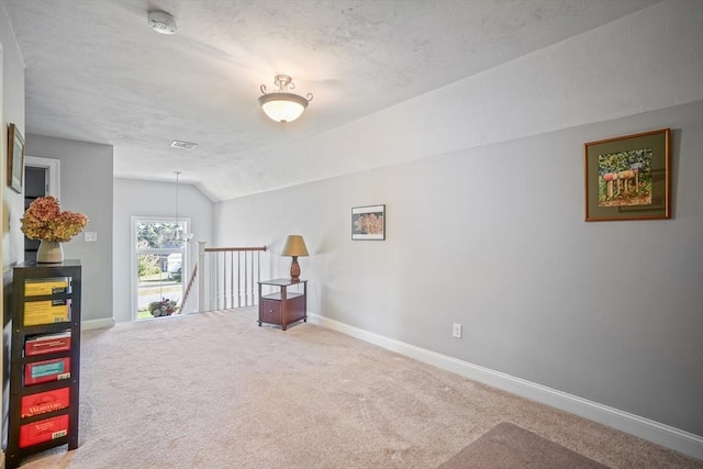 interior space with carpet floors, baseboards, vaulted ceiling, and visible vents