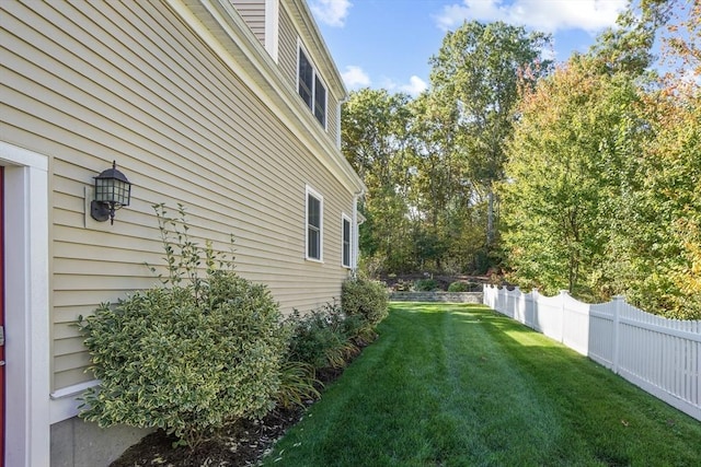 view of side of property with a lawn and fence