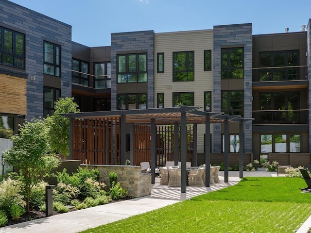 view of property's community featuring a yard, a pergola, and a patio