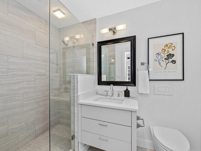 bathroom featuring toilet, vanity, and an enclosed shower