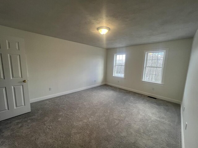 unfurnished room with dark colored carpet