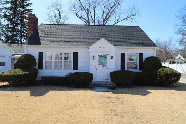 view of front of house featuring a chimney, roof with shingles, and fence