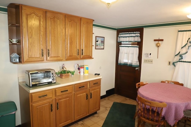 kitchen featuring brown cabinetry, light floors, open shelves, a toaster, and light countertops