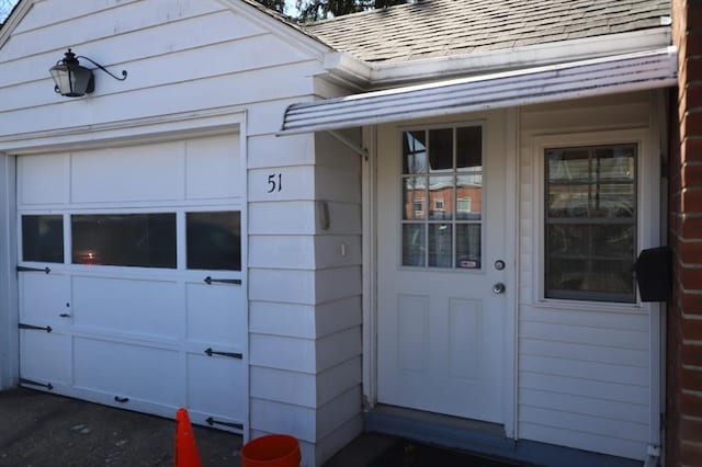 doorway to property with roof with shingles