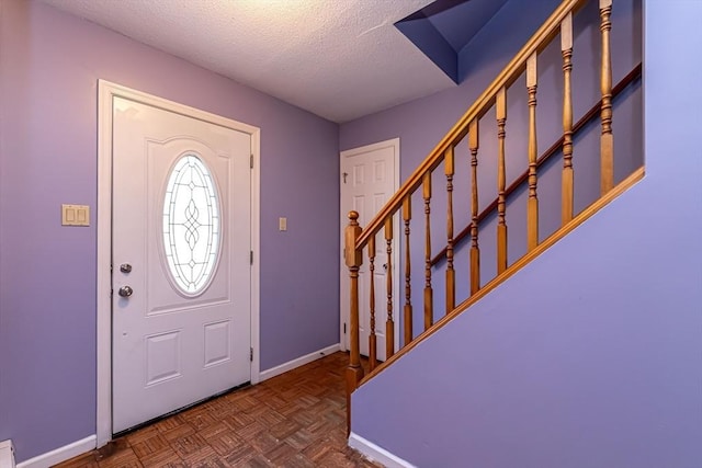 foyer entrance featuring dark parquet flooring and a textured ceiling