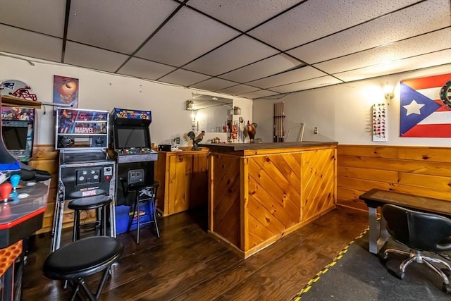 bar with a paneled ceiling, dark hardwood / wood-style floors, and wood walls