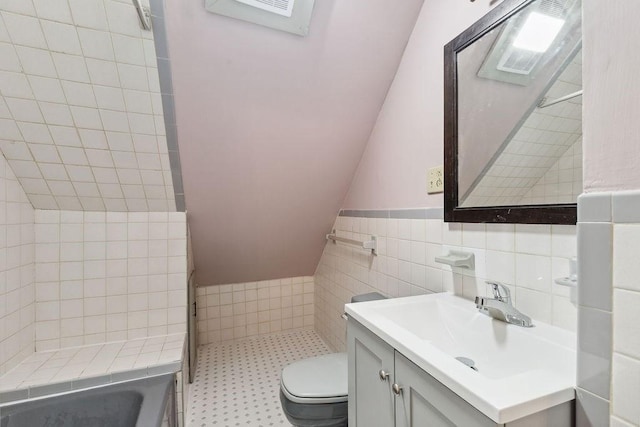 bathroom featuring toilet, vanity, lofted ceiling, tile walls, and a shower