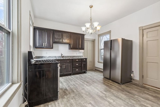 kitchen featuring dark brown cabinets, black gas range, light wood-type flooring, freestanding refrigerator, and a sink