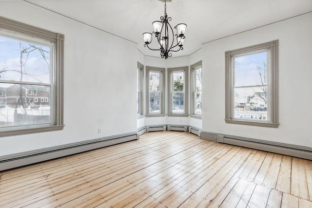 unfurnished dining area with a wealth of natural light, a notable chandelier, baseboard heating, and wood-type flooring