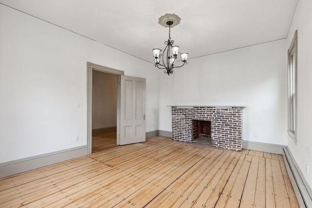 unfurnished living room featuring baseboards, an inviting chandelier, a fireplace, hardwood / wood-style flooring, and a baseboard heating unit