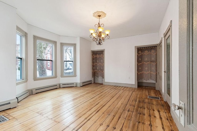 unfurnished room featuring visible vents, baseboards, an inviting chandelier, and hardwood / wood-style flooring