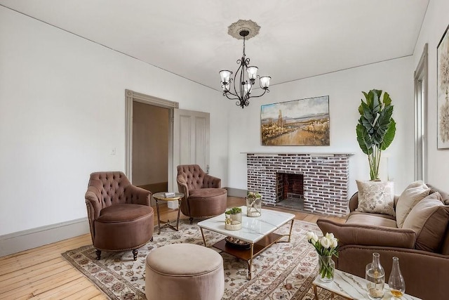 living area featuring baseboards, wood-type flooring, an inviting chandelier, and a tiled fireplace