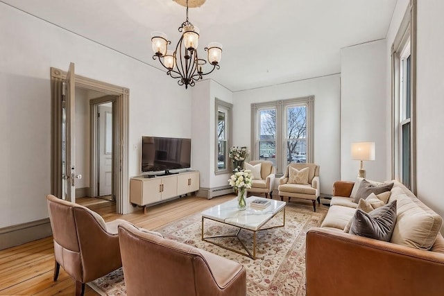 living area with a baseboard heating unit, light wood-type flooring, an inviting chandelier, and a baseboard radiator