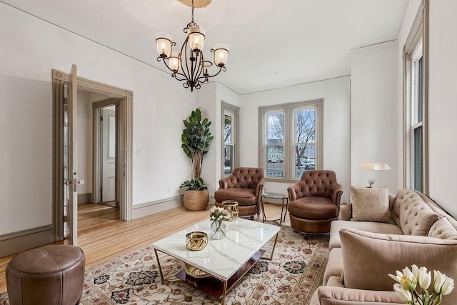 living area with baseboards, a notable chandelier, and wood finished floors