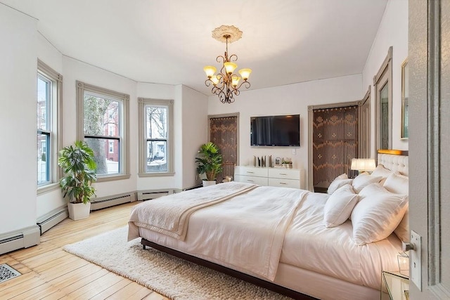 bedroom with multiple windows, an inviting chandelier, and hardwood / wood-style flooring