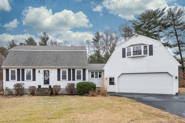 colonial inspired home featuring a gambrel roof, driveway, a front lawn, and roof with shingles